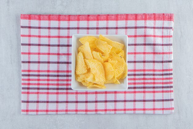 Weiße Schüssel mit leckeren Ripple-Chips auf Stein.