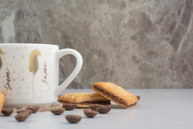 Weiße Tasse Kaffee mit Crackern und Kaffeebohnen auf weißem Hintergrund. Hochwertiges Foto