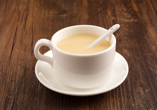 Weiße Tasse Kaffee über einem Holztisch