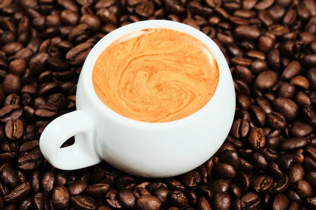 Weiße tasse mit espressokaffee und kaffeebohnen, flach gelegt. nahansicht. morgen starker italienischer kaffee mit duftendem schaum, draufsicht. kaffeeidee zum frühstück