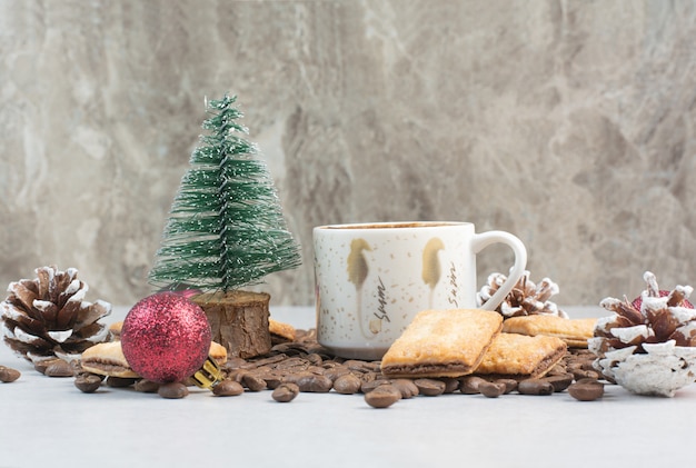 Weiße Tasse voll Kaffee mit Kaffeebohnen und Tannenzapfen. Hochwertiges Foto