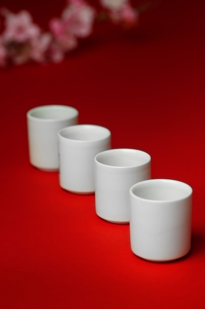 Weiße Tassen des hohen Winkels auf rotem Hintergrund