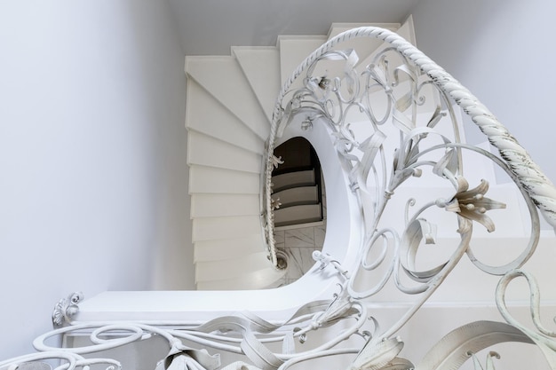 Weiße treppe mit weiß geschmiedetem spiralgeländer als dekoratives element. konzept der innenarchitekturelemente