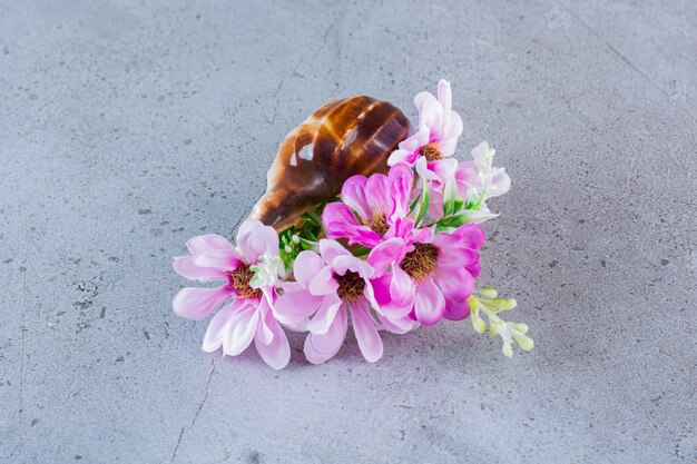 Weiße und rosa Blüten mit Muscheln auf Grau