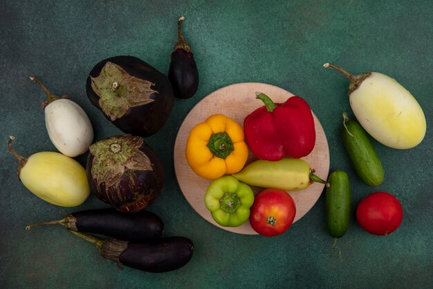 Weiße und schwarze Aubergine der Draufsicht mit Paprika-Tomaten auf einem Ständer und Gurken auf einem grünen Hintergrund