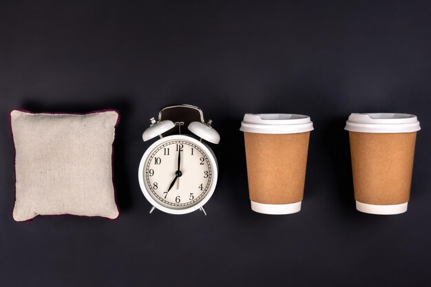 Weiße Wecker-Einwegbecher und ein kleines Kissen auf dunklem Hintergrund