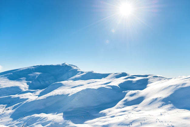 Weiße winterberge mit schnee und strahlender sonne und sonnenstrahlen