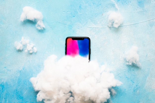 Weiße Wolke auf Mobiltelefon gegen blauen strukturierten Hintergrund