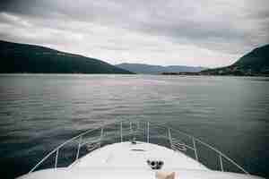 Kostenloses Foto weiße yacht kreuzt meer und hinterlässt berge mit nebel