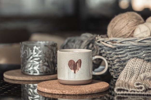 Kostenloses Foto weißer becher mit herz und weidenkorb mit fadenkugeln