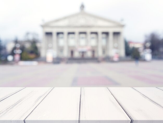 Weißer Beschaffenheitsschreibtisch vor öffentlichem Gebäude der Unschärfe