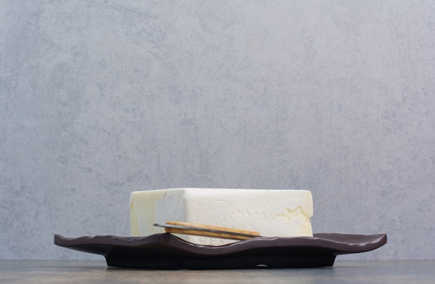 Weißer Käse auf schwarzem Teller mit Messer