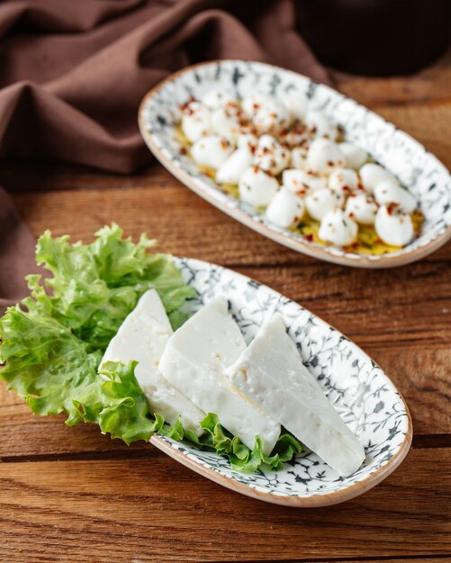 Weißer Käse der Draufsicht mit grünem Salat auf dem braunen hölzernen Schreibtischessen-Mahlzeitfrühstückskäse