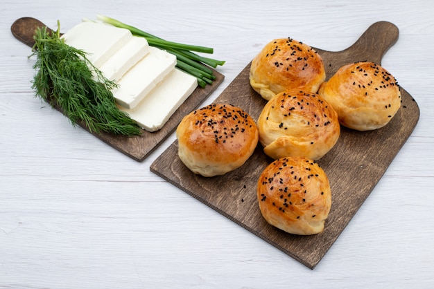 Weißer Käse der Draufsicht zusammen mit Grün und Brötchen auf dem hellen Hintergrundnahrungsmittelmahlzeitbrotbrötchen