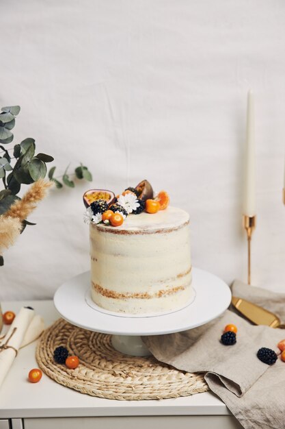 Weißer Kuchen mit Beeren und Passionsfrüchten neben einer Pflanze