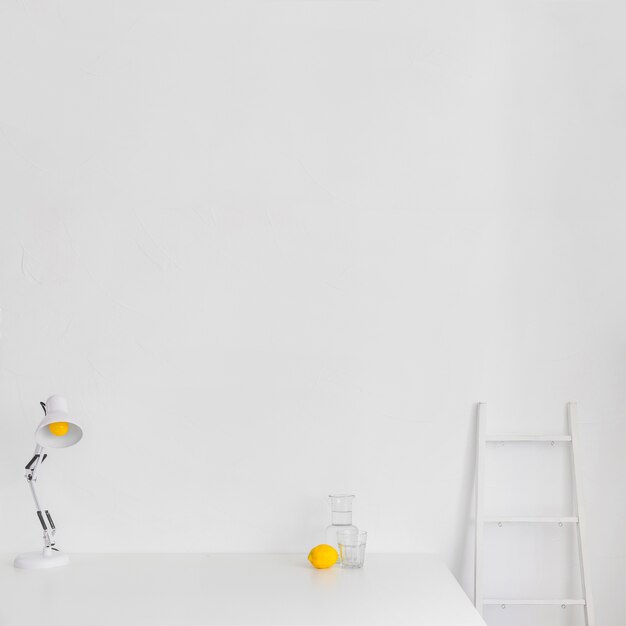 Weißer minimalistischer Arbeitsplatz mit Leiter und Zitrone