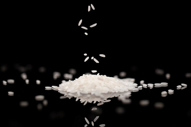 Weißer Reis fällt auf schwarzem Glastisch im dunklen Raum