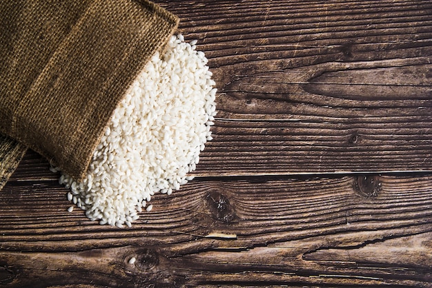 Weißer Reis zerstreut vom Sack auf Tabelle