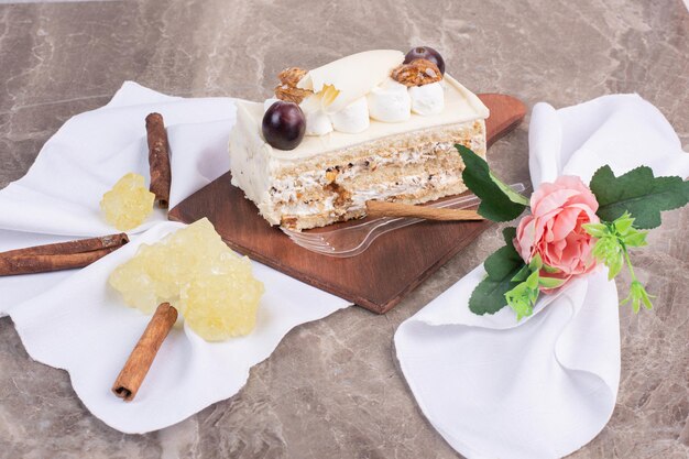Weißer Schokoladenkuchen auf Holzbrett mit Stoff und Süßigkeiten.