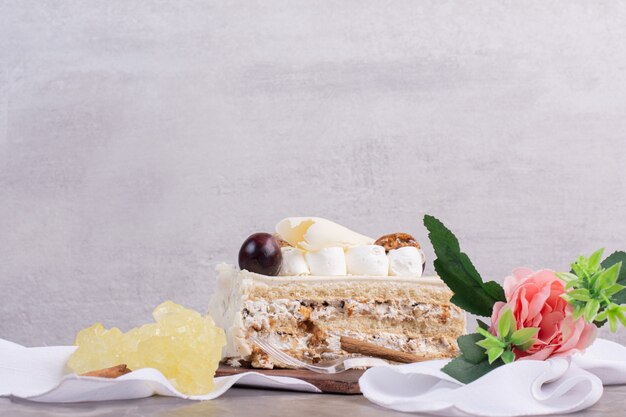 Weißer Schokoladenkuchen mit Bonbons und Blume auf Marmortisch.