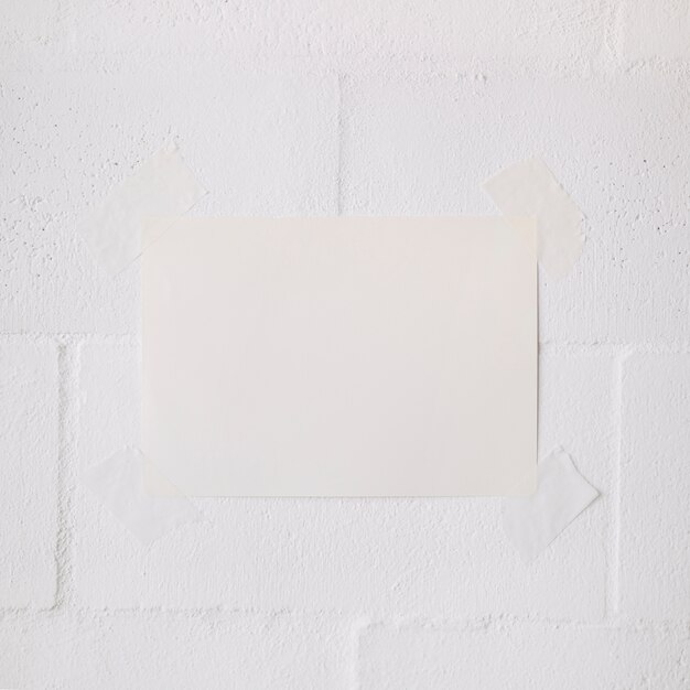 Weißer Stock des leeren Papiers mit Band auf weißem Wandhintergrund