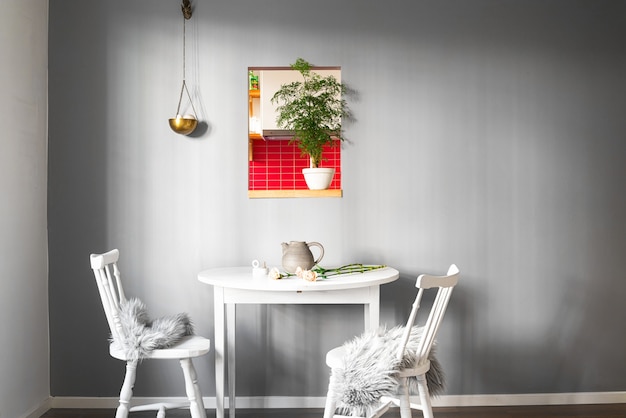 Weißer Tisch mit zwei Stühlen in einem Raum mit einem schönen Interieur und einem Bild an der Wand