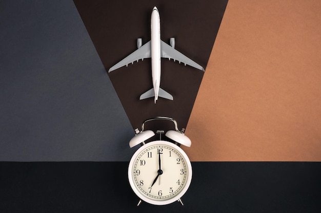 Kostenloses Foto weißer wecker und flugzeugmodell auf papierhintergrund, draufsicht