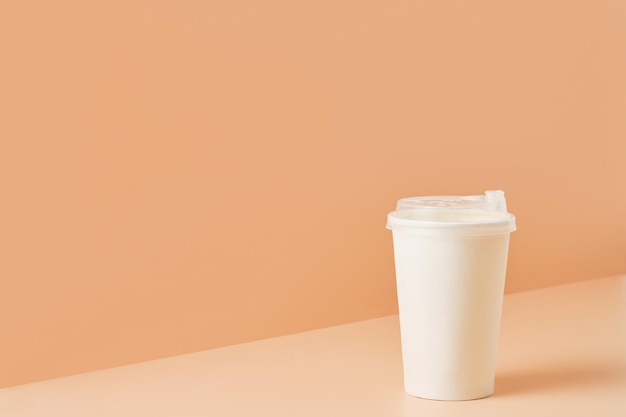 Weißes Glas ohne Markenzeichen für Getränke auf farbigem Hintergrund, Nahaufnahme mit Kopierfläche für Text.Umweltfreundliche Tasse aus Karton