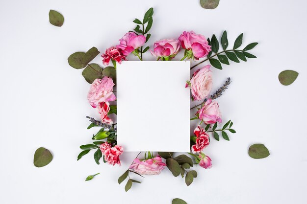 Weißes leeres Papier auf schönen Blumen über dem weißen Hintergrund