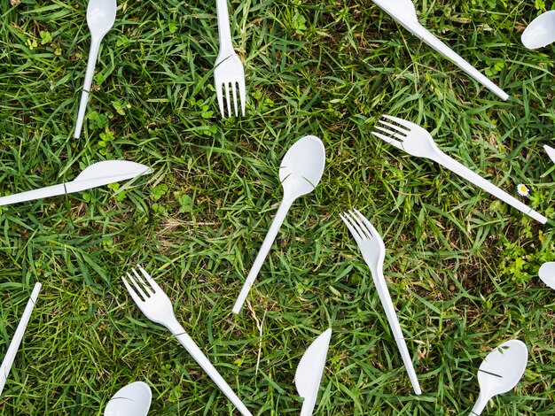 Weißes Plastiktischbesteck auf grünem Gras am Park