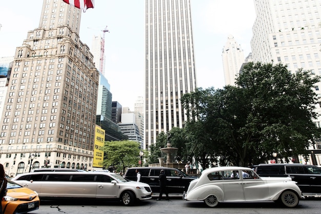 Weißes Retro- Auto und neue Limousine fahren entlang die Straße in NEW York
