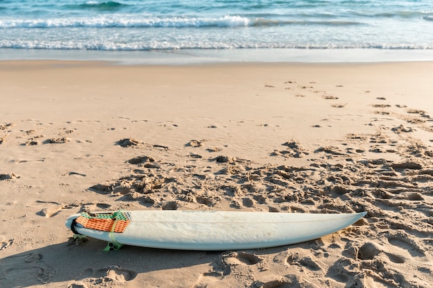 Weißes Surfbrett, das auf Sand liegt
