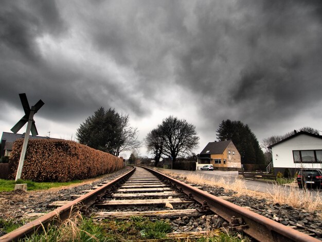 Weitwinkelaufnahme der Eisenbahnschienen, umgeben von Bäumen unter einem bewölkten Himmel