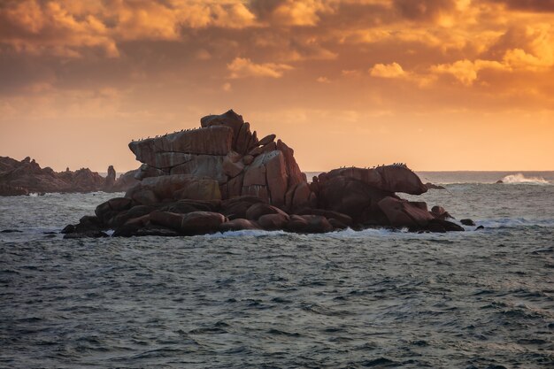 Weitwinkelaufnahme einer Insel mit Klippen, die während des Sonnenuntergangs vom Wasser umgeben ist