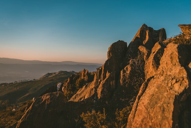 Weitwinkelaufnahme einer Klippe auf einem Berg unter der Sonne und einem klaren blauen Himmel