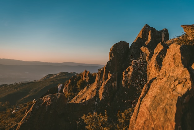 Weitwinkelaufnahme einer Klippe auf einem Berg unter der Sonne und einem klaren blauen Himmel