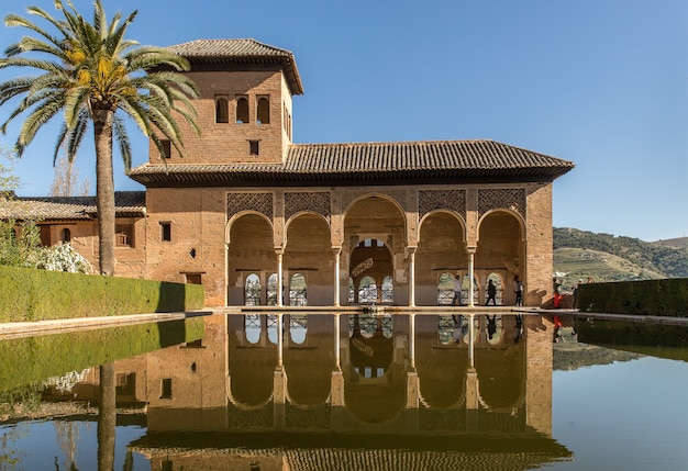 Weitwinkelaufnahme eines Gebäudes vor dem Wasser und neben dem Baum in Spanien