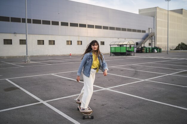 Weitwinkelaufnahme eines Mädchens auf einem Skateboard hinter einem Gebäude