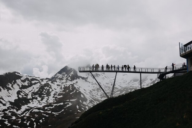 Weitwinkelaufnahme von Menschen auf einem Dock in der Nähe von schneebedeckten Bergen