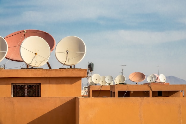 Weitwinkelaufnahme von weißen Satellitenschüsseln auf dem Dach eines Gebäudes