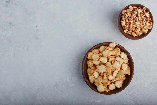 Weizen Popcorns und Cracker in einer Holzschale auf Steinoberfläche, Draufsicht.