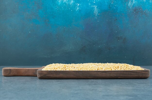 Weizenkorn ordentlich auf einem Holzbrett auf blauem Hintergrund gestapelt. Foto in hoher Qualität