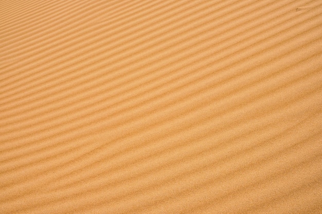 Wellenförmiger sandhintergrund für sommerdesigns oder kulissen natürlicher sandstein-texturhintergrund sand am strand als hintergrund