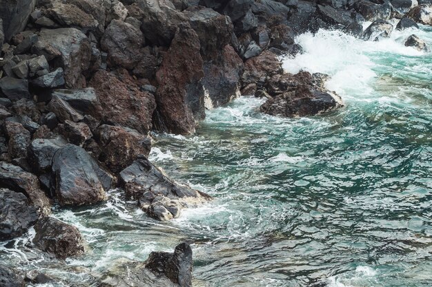 Wellenförmiges Wasser der Nahaufnahme am felsigen Ufer