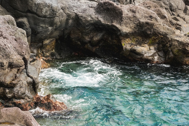 Wellenförmiges Wasser der oben genannten Ansichtnahaufnahme am felsigen Ufer