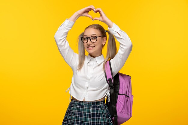 Weltbuchtag-Schulmädchen niedlich, Herz mit Händen mit rosa Rucksack zeigend