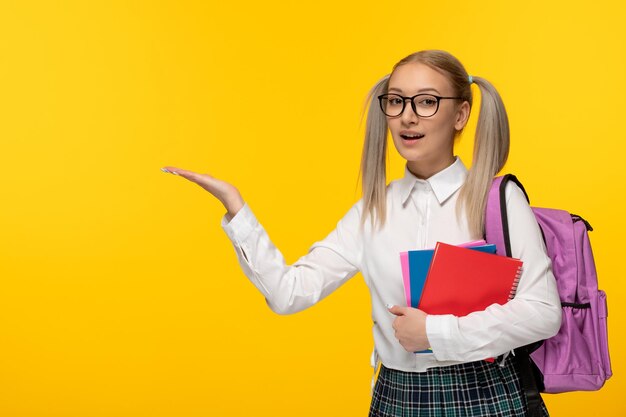 Welttag des Buches glücklich lächelndes blondes Schulmädchen, das Bücher mit Rucksack hält