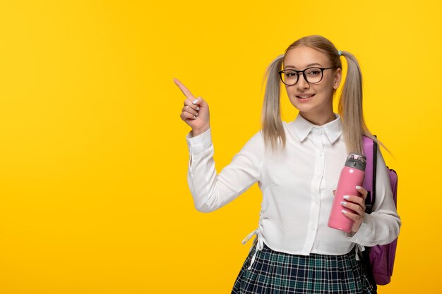 Welttag des Buches glückliches blondes Schulmädchen in niedlicher Uniform mit rosa Flasche