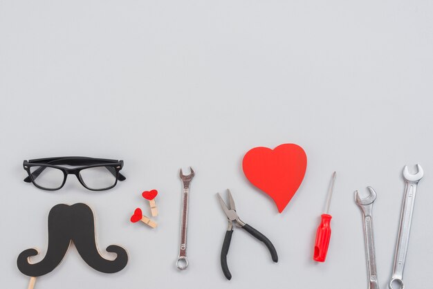 Werkzeuge mit Papierschnurrbart und rotem Herzen