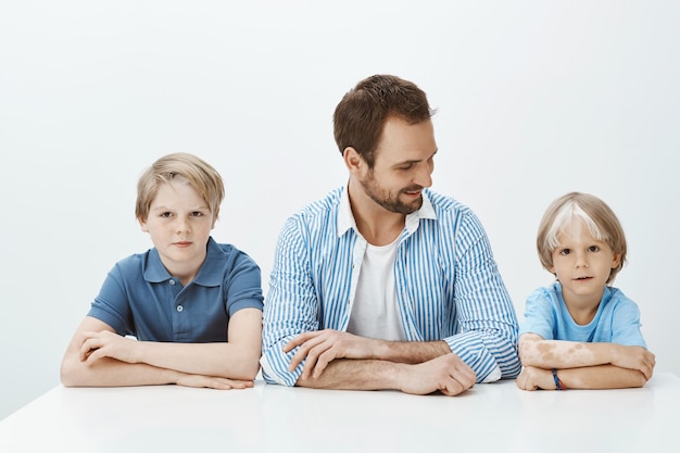 Wie der Vater wie die Söhne. Porträt der schönen glücklichen Familie, die mit den Händen zusammen sitzt